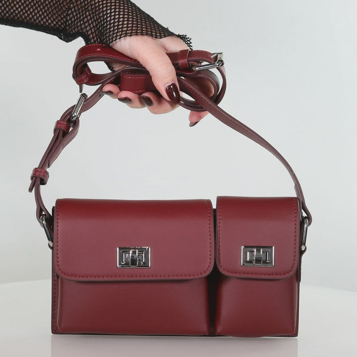Red handbag held by a hand against a white background