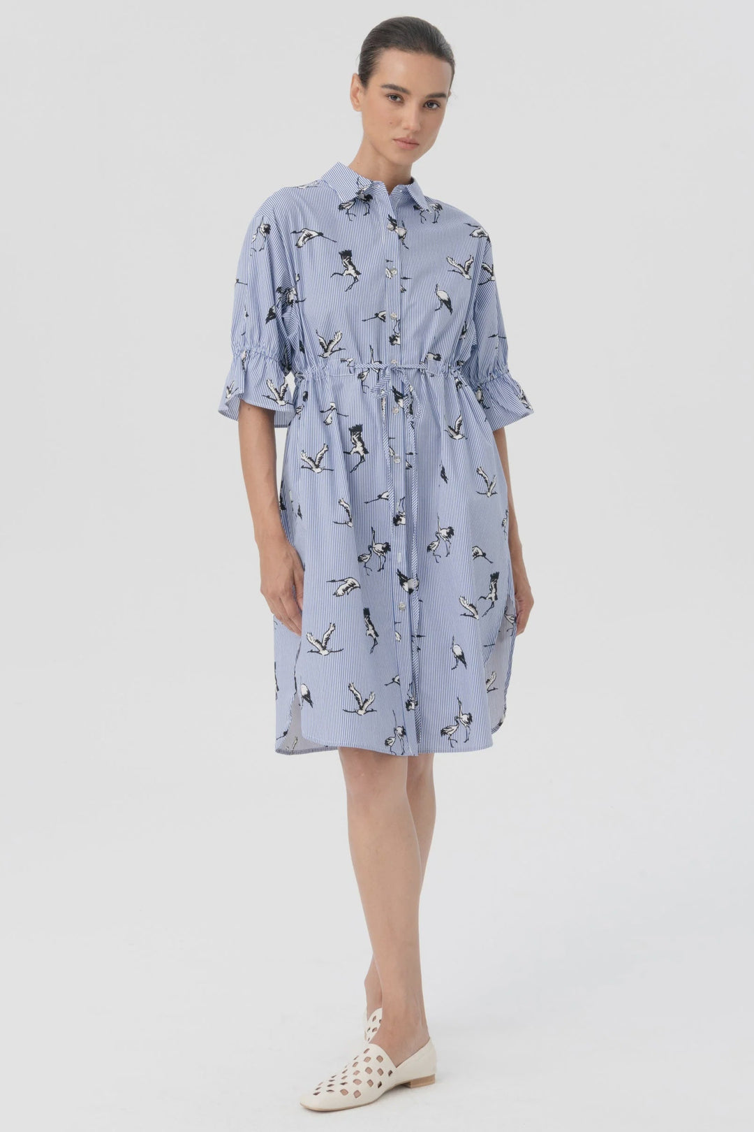 Woman wearing a light blue dress with a pattern on a white background