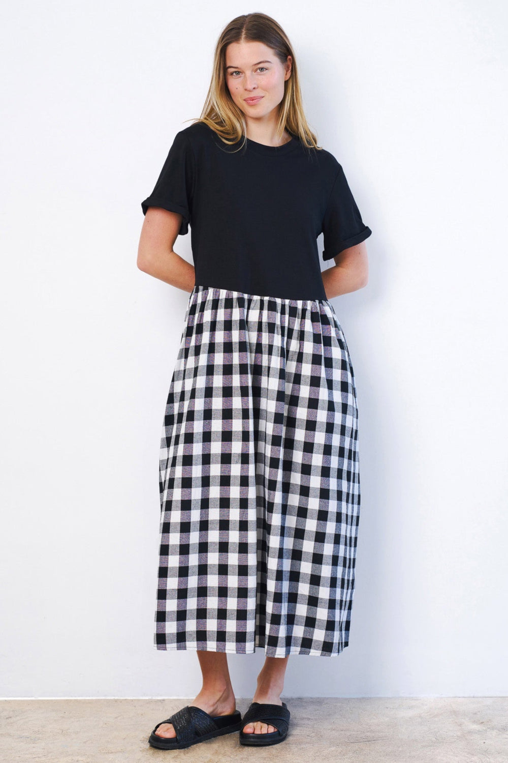 Woman wearing a black t-shirt and a black and white checkered skirt against a white background