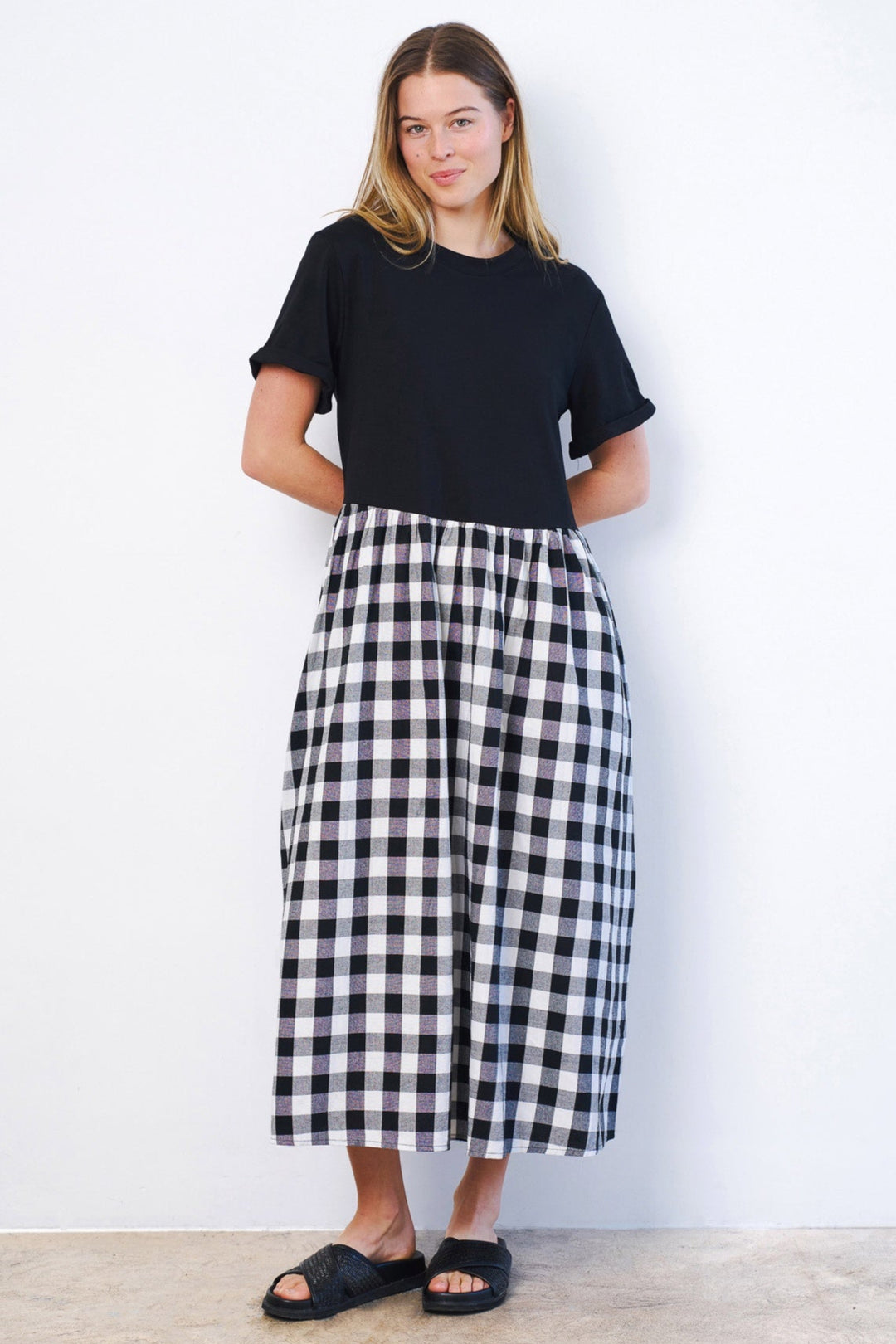 Woman wearing a black t-shirt and a black and white checkered skirt against a white background