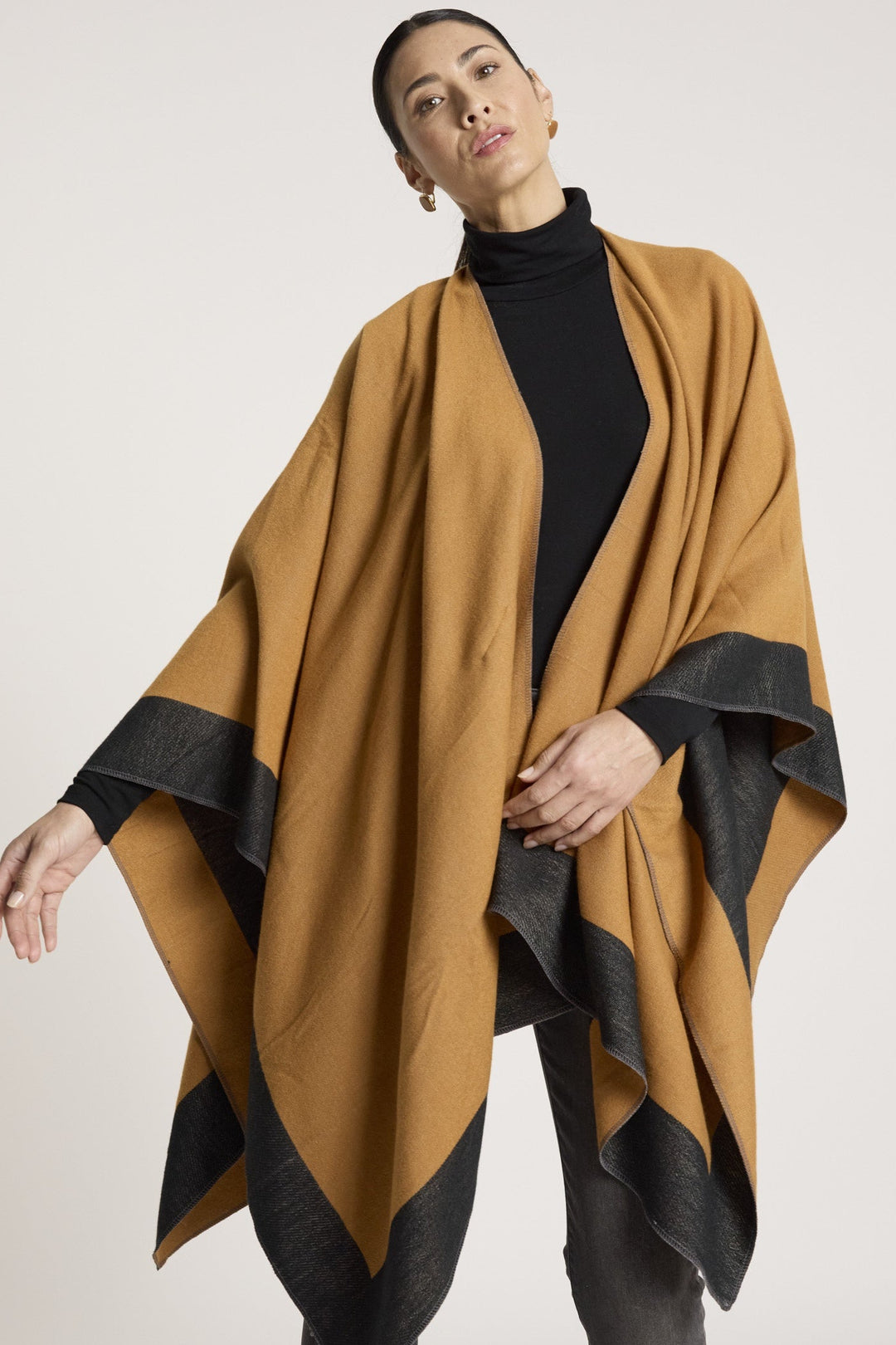 Woman wearing a brown and black poncho against a white background