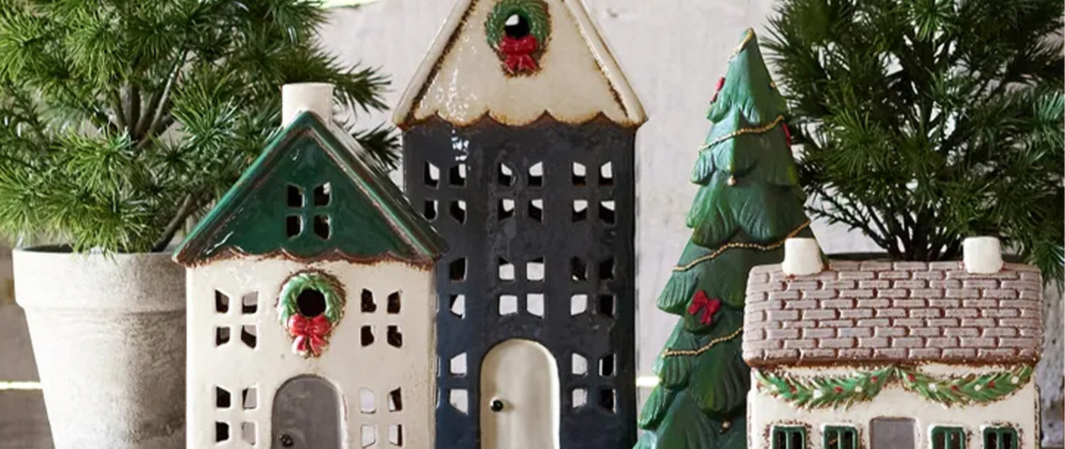 Decorative Christmas decorations, ceramic houses with Christmas trees and wreaths on a neutral background