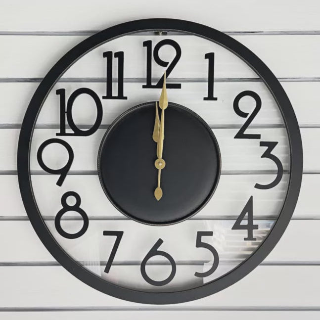 Black wall clock with gold hands on a white wooden background