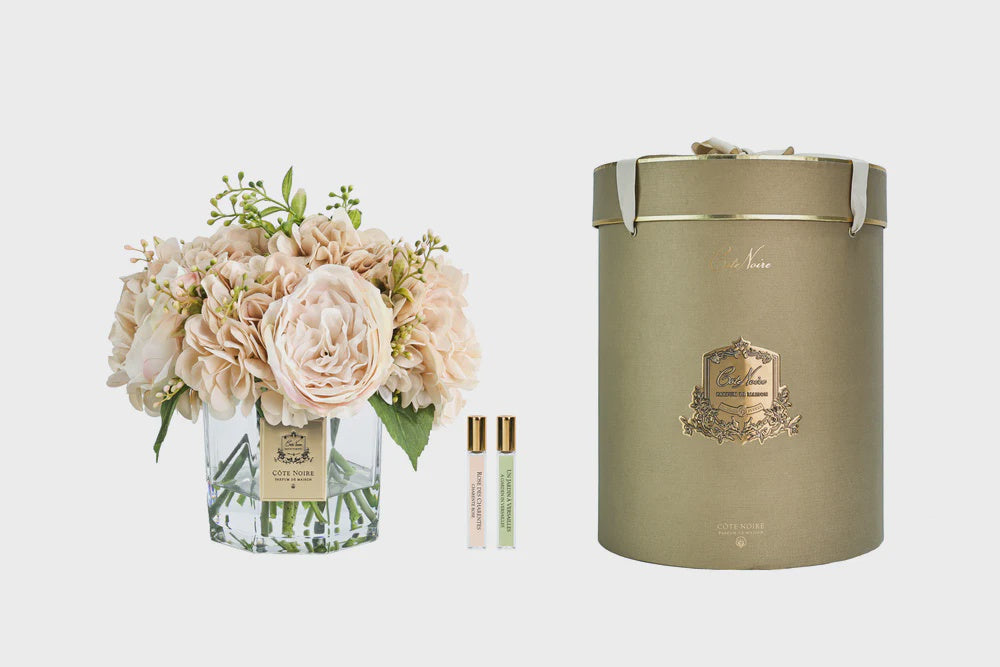 Cote Noire floral arrangement, perfume bottles, and a decorative box on a light gray background