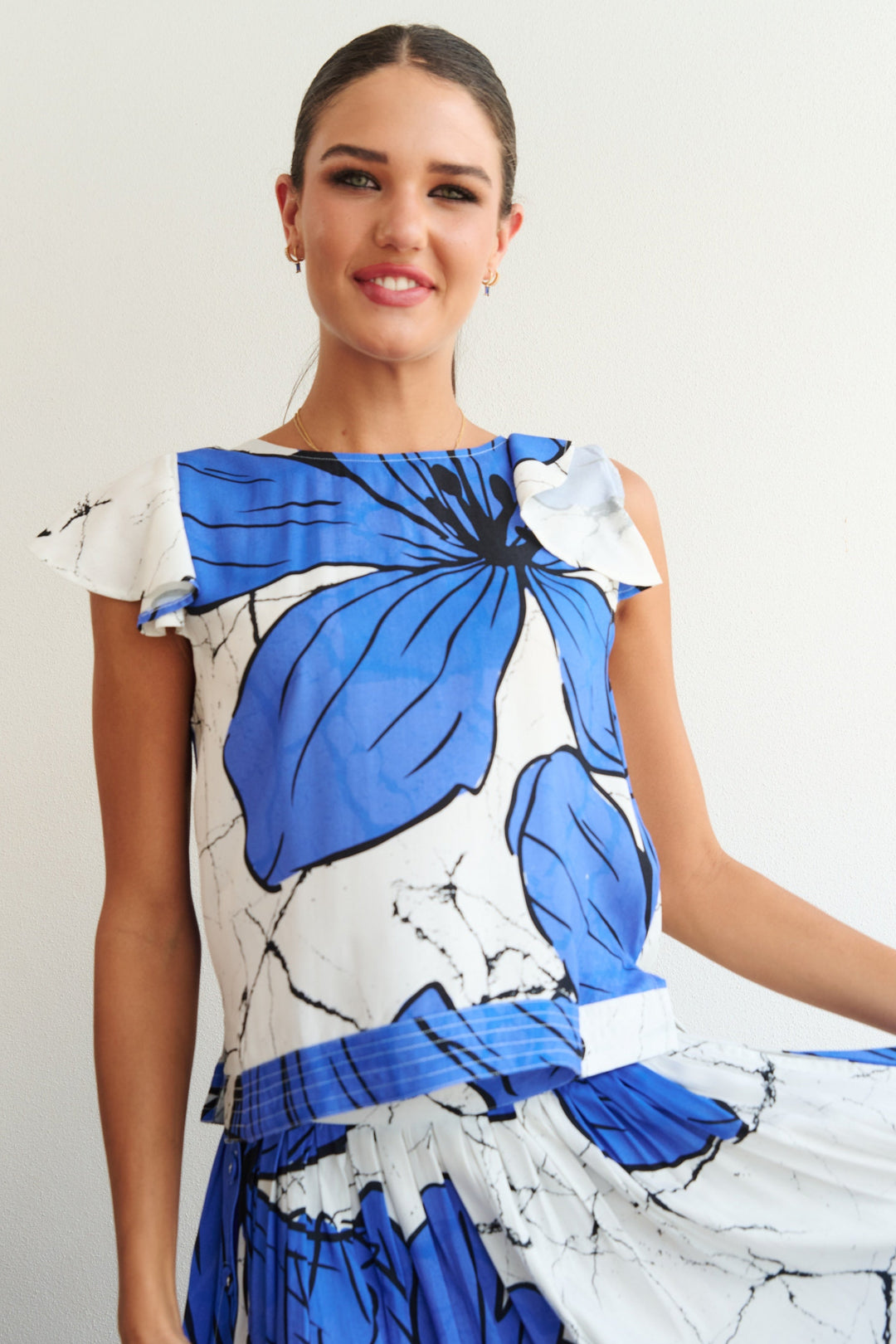 Woman wearing a blue and white dress with a floral pattern against a plain background