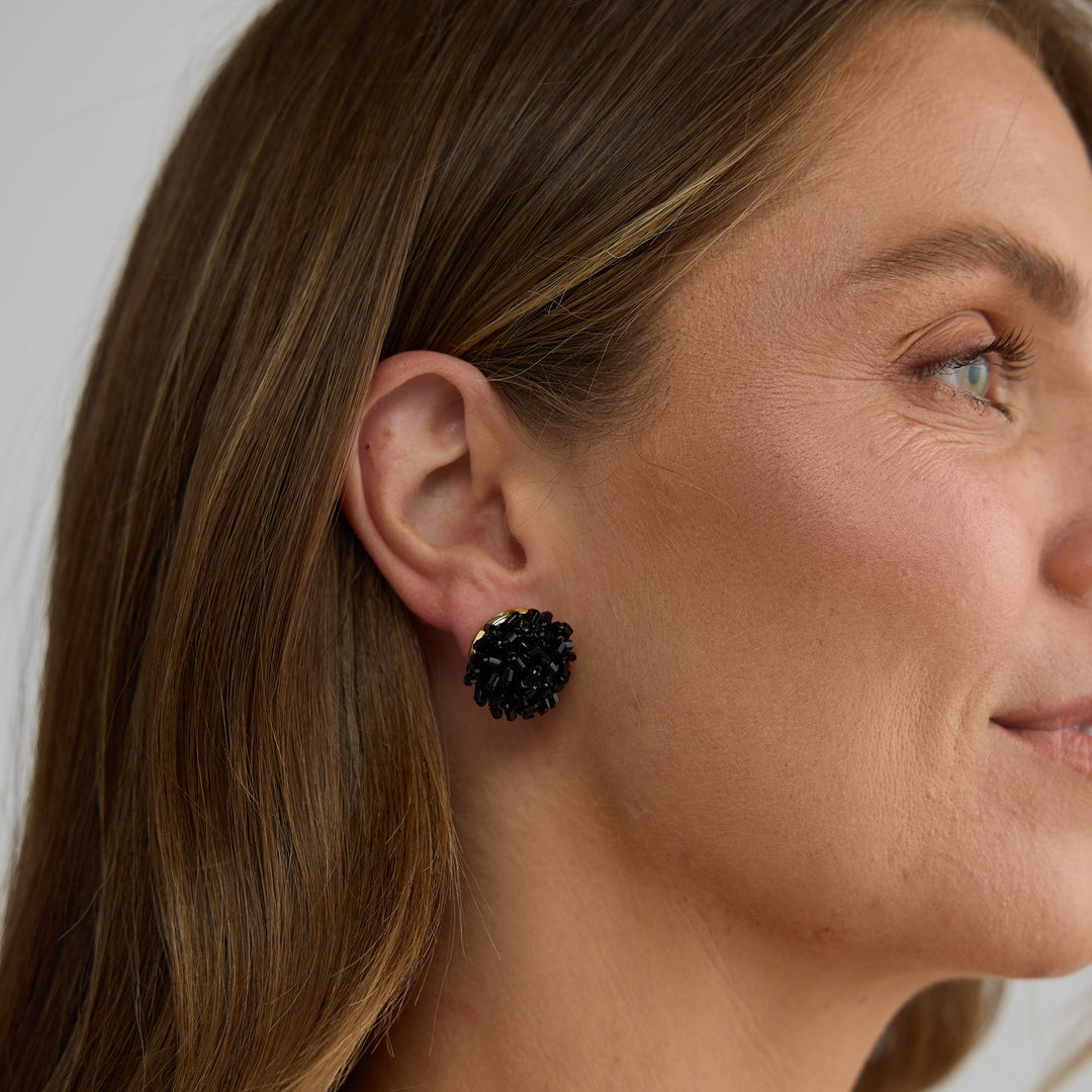 Woman wearing black floral earrings against a neutral background