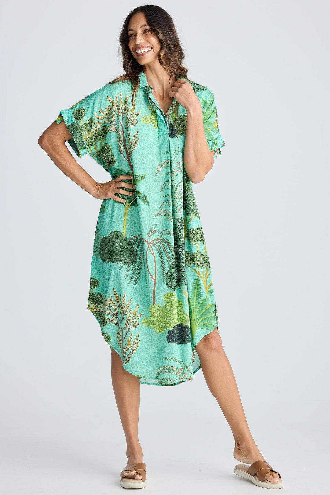 Woman wearing a green tropical patterned dress on a white background