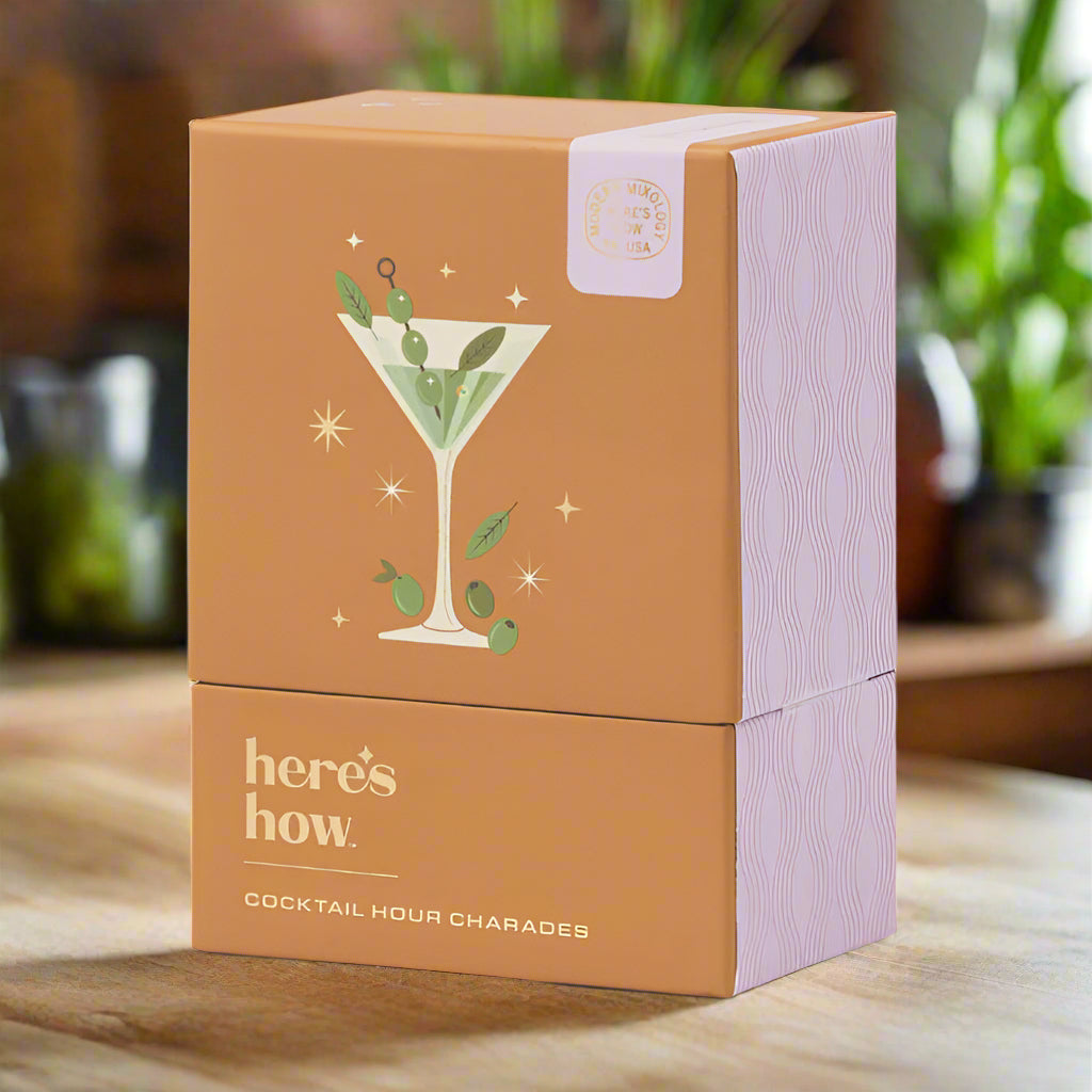Orange packaging box with cocktail illustration and 'here's how' text on a light gray background