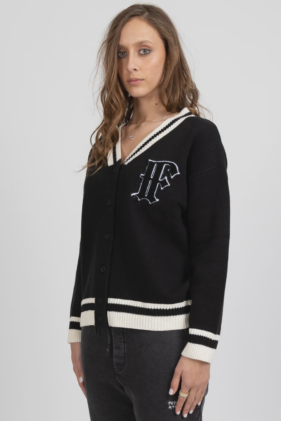 Woman wearing a black cardigan with white trim on a gray background