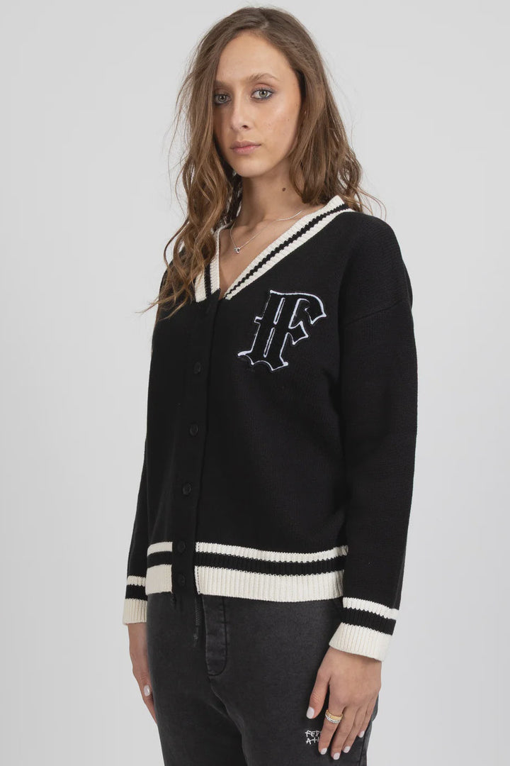 Woman wearing a black cardigan with white trim on a gray background