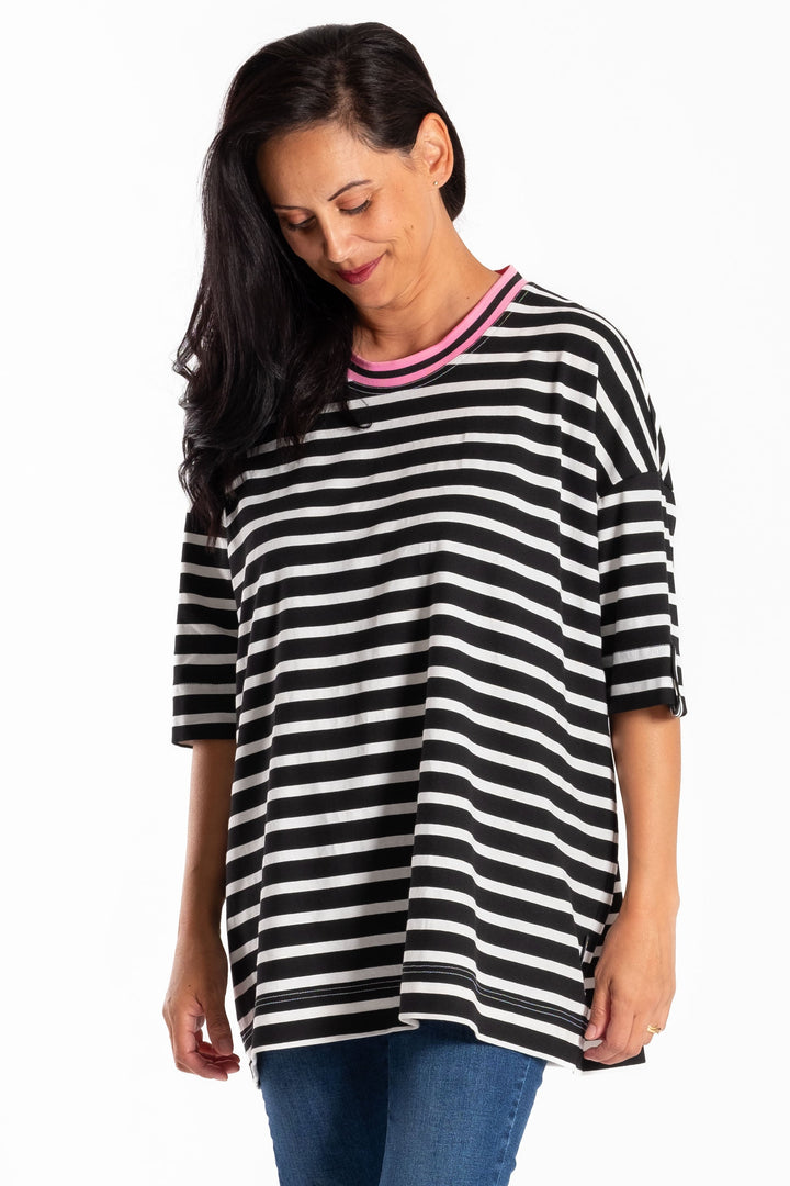 Woman wearing a jellicoe black and white striped teeand blue jeans on a white background