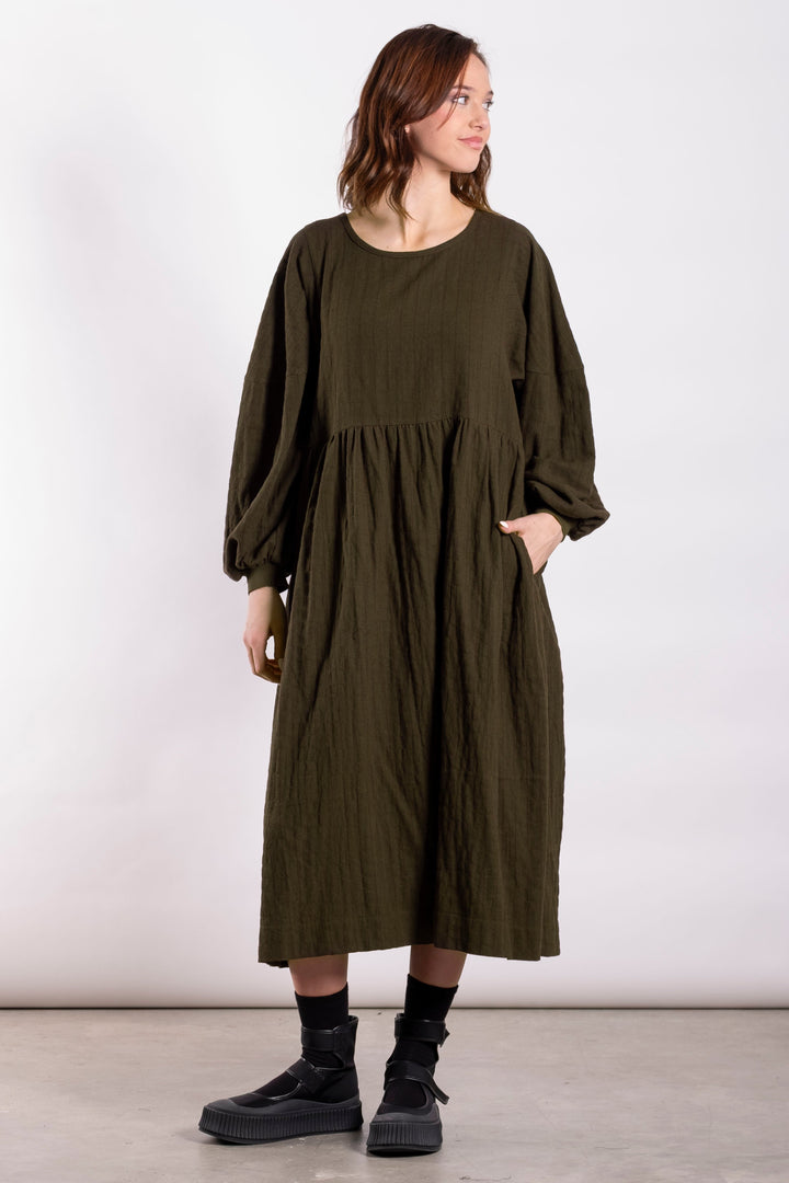 Woman wearing a green dress standing against a white background