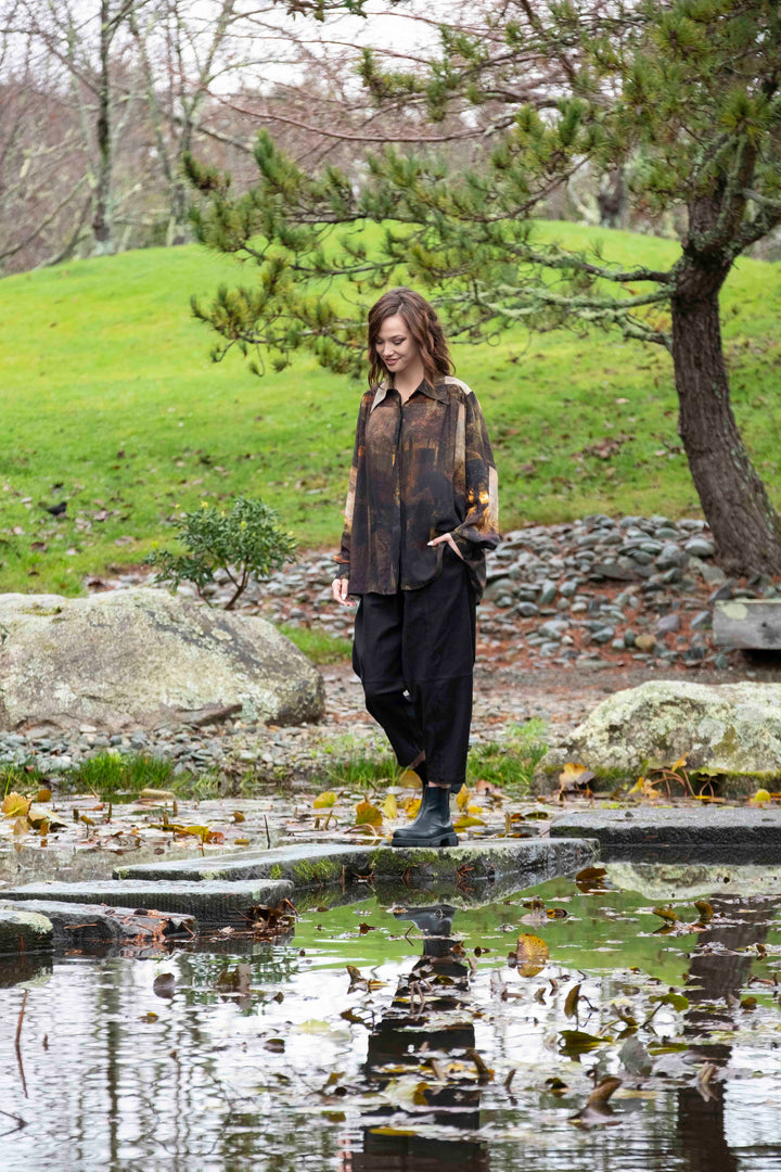 Woman standing by a pond in a park with trees and grass in the background