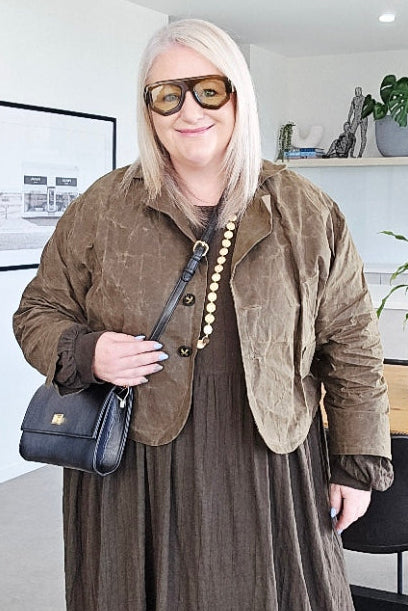 Person wearing a khaki jacket coat in an indoor setting with modern decor.