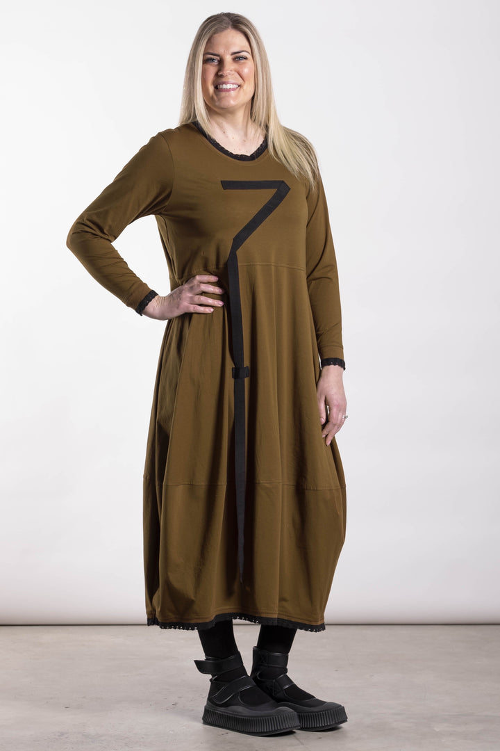 Woman wearing a long brown dress with a black number 7 design on a white background