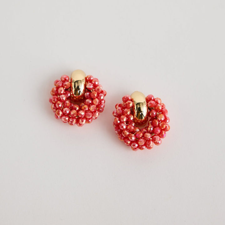 Pair of red beaded earrings on a light gray background