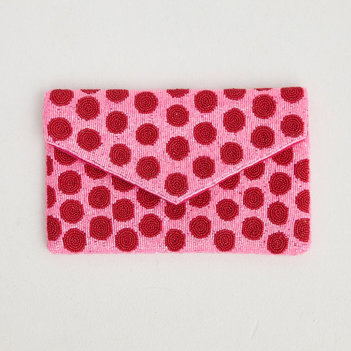 Pink pouch with red polka dots on a light gray background