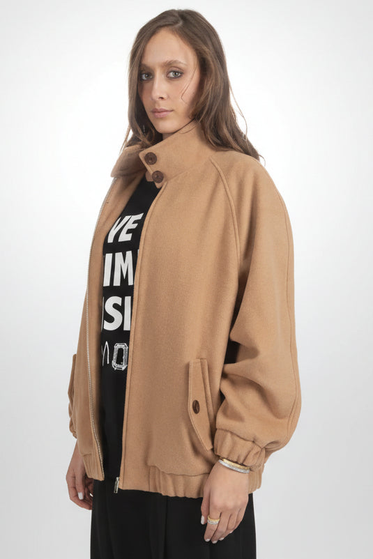 Woman wearing a tan jacket over a black graphic t-shirt on a white background