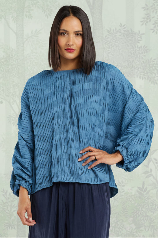 Woman wearing a blue top and navy pants on a white background