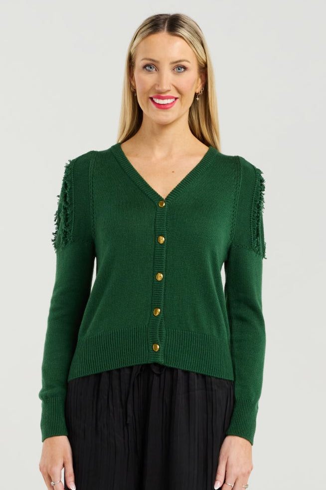 Woman wearing a green cardigan and black pants on a white background