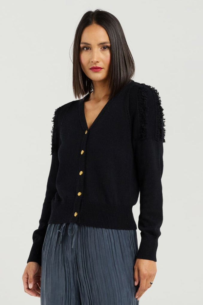 Woman wearing a black cardigan and blue pleated pants on a white background