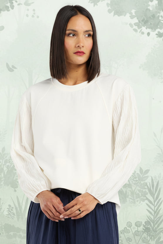 Woman wearing a white top and navy blue skirt on a light gray background