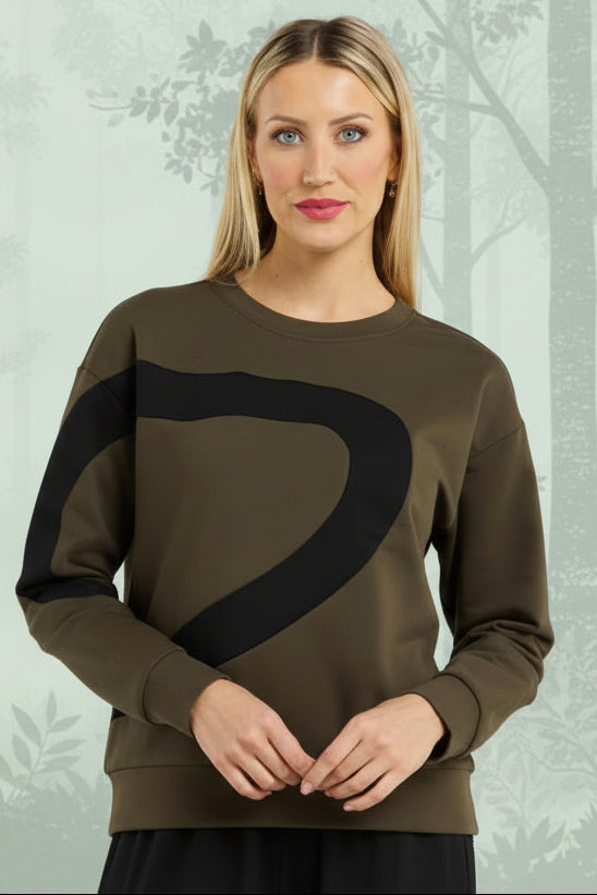 Woman wearing a green sweater with a black design and black pants on a white background