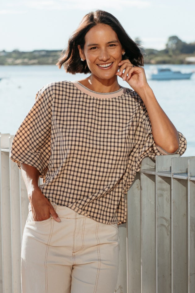 Woman standing on a wooden deck by a waterfront with boats in the background