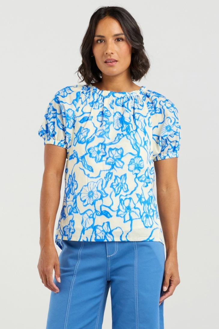 Woman wearing a blue floral top and blue pants on a white background