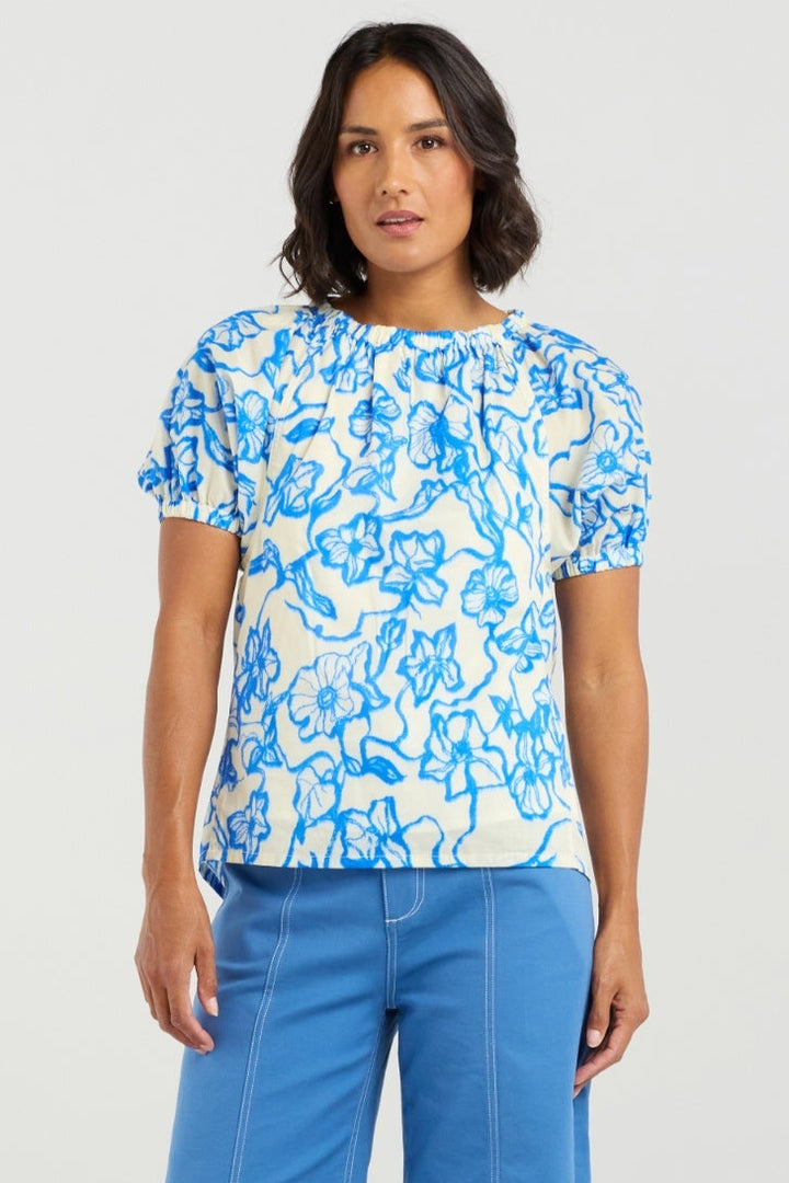 Woman wearing a blue floral top and blue pants on a white background