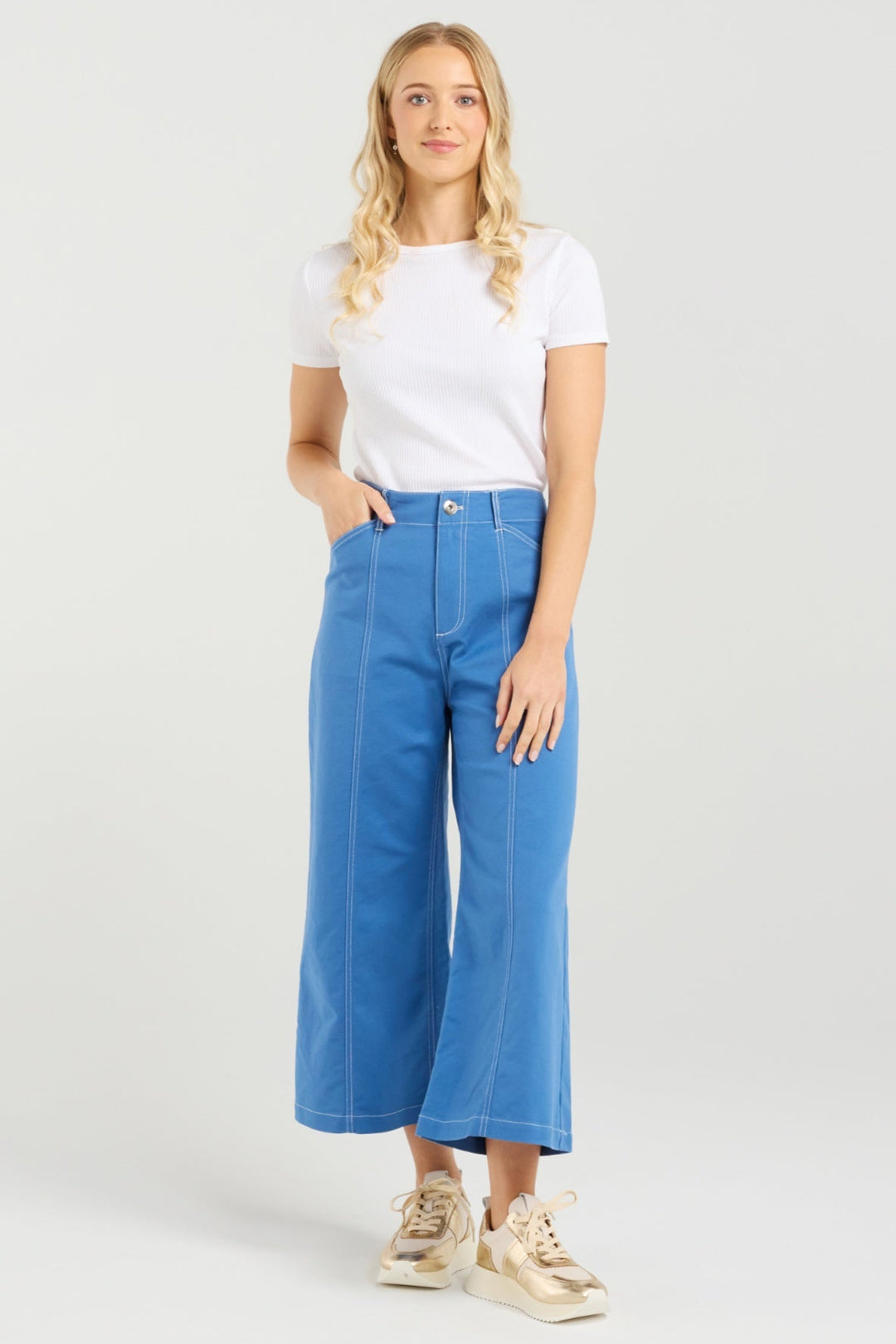Woman wearing a white t-shirt and blue jeans on a plain background