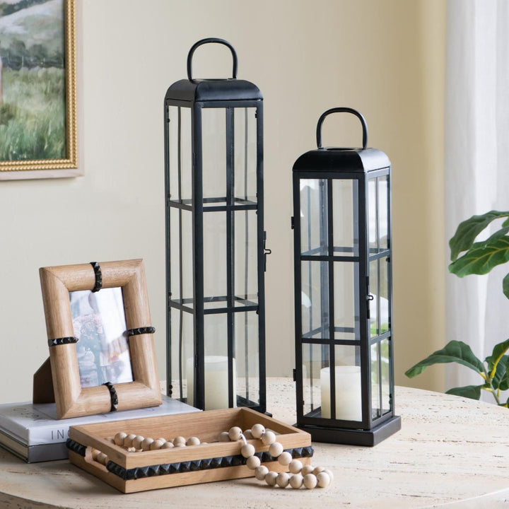 Decorative lanterns and photo frame on a table with a painting in the background