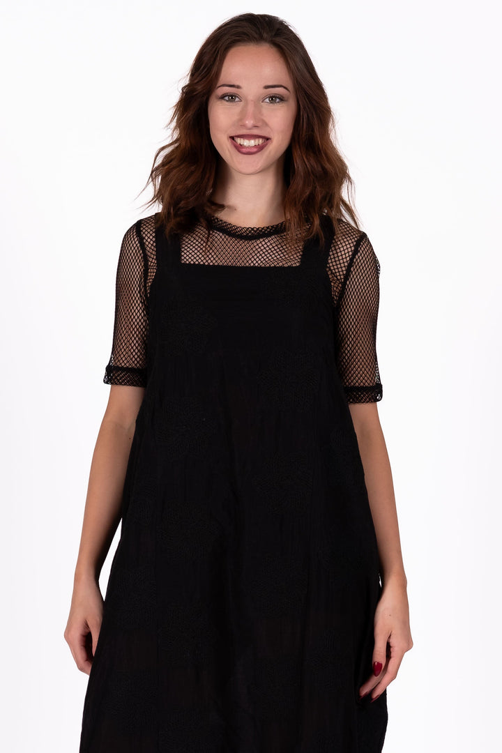 Woman wearing a black dress AND FISHNET TEE UNDERNEATH on a white background