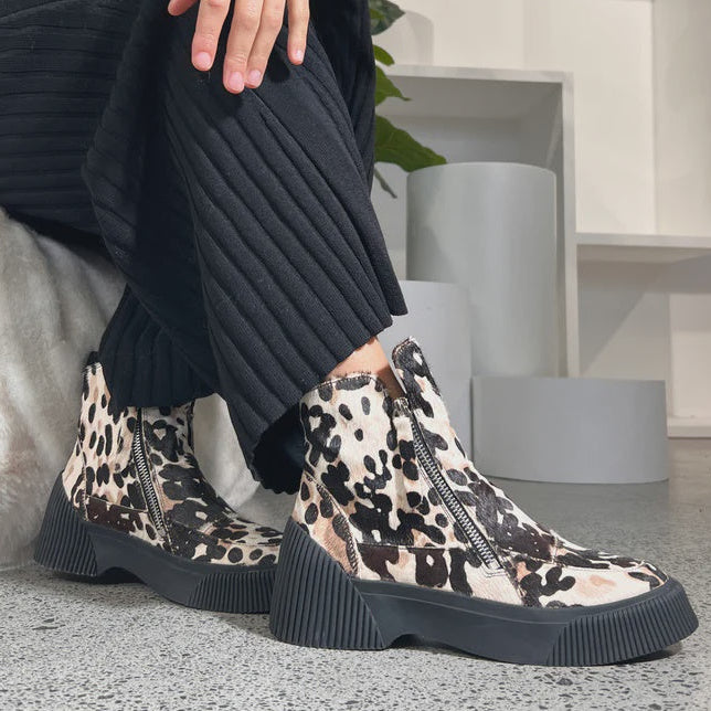 Person wearing leopard print boots in a modern indoor setting