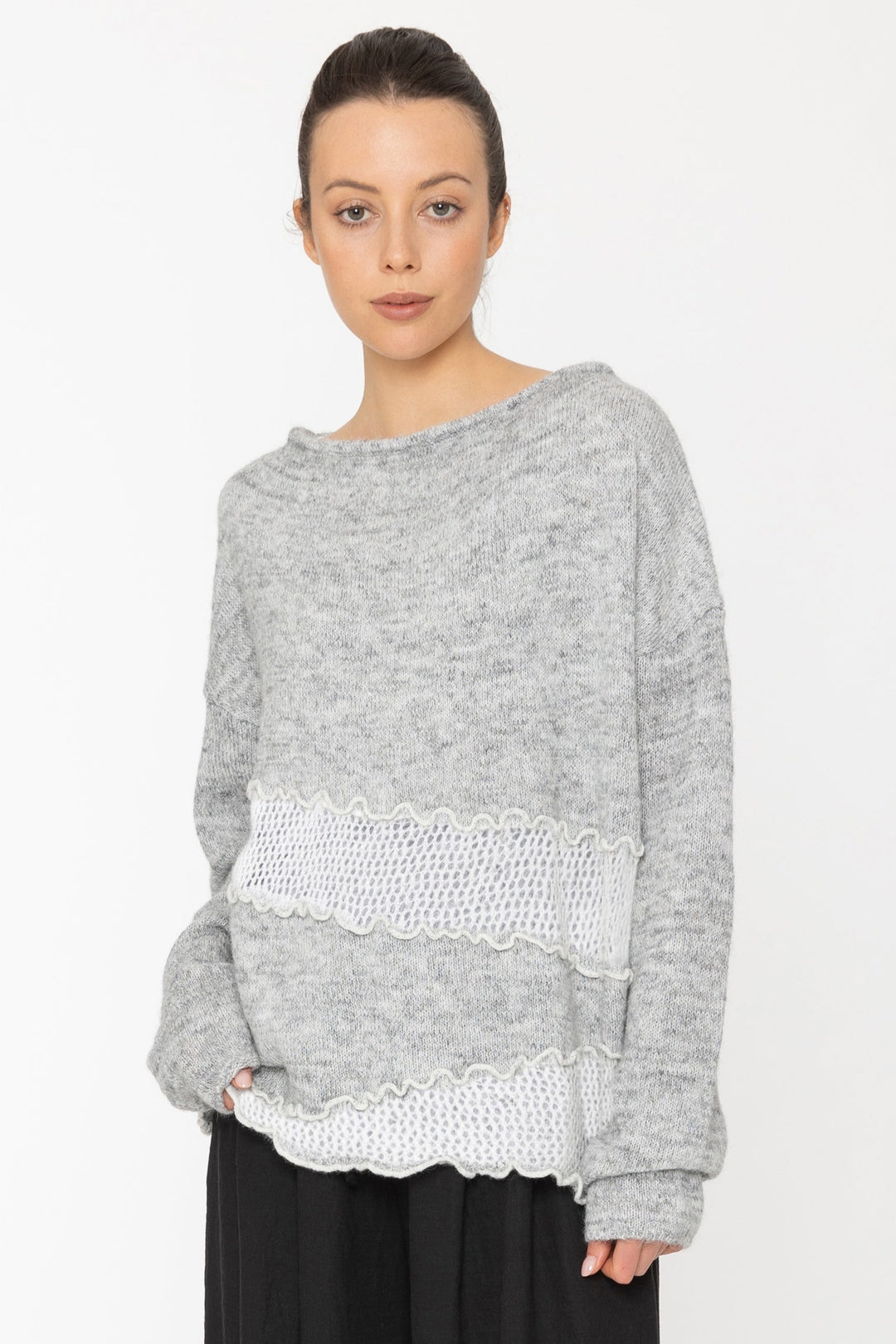 Woman wearing a gray sweater and black pants on a white background