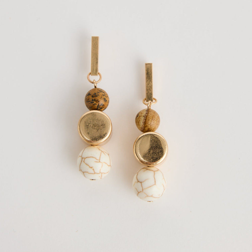 Pair of gold and white hair accessories on a light gray background