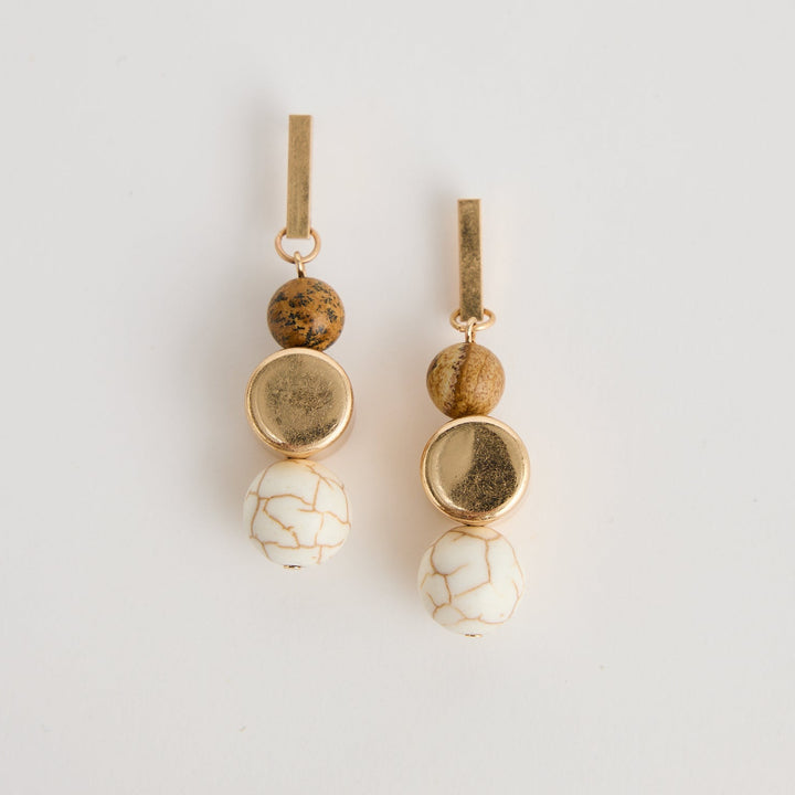 Pair of gold and white hair accessories on a light gray background