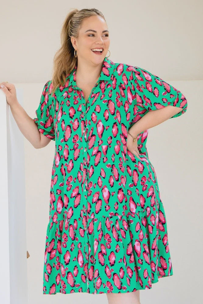 Woman wearing a green dress with pink floral pattern against a white background