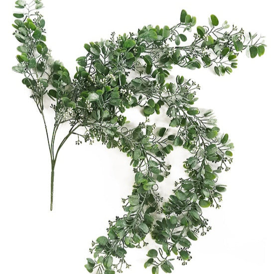 Artificial green leafy branch on a white background