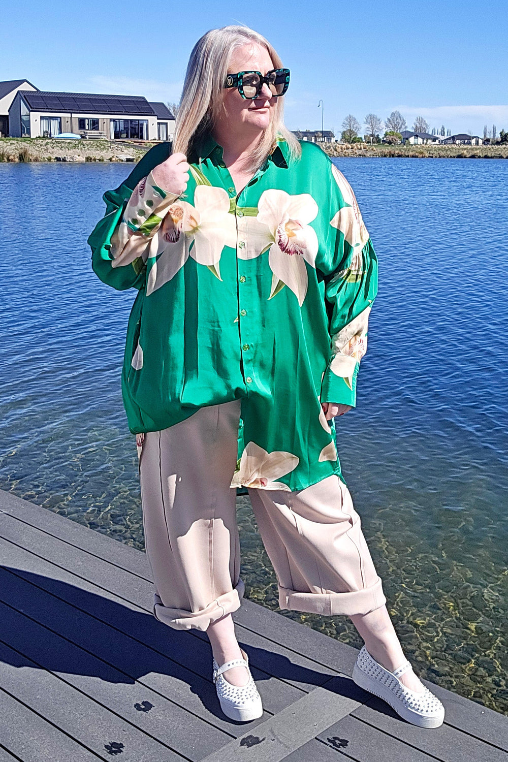 WOMEN WEARING A GREEN SHIRT & BONE COLOURED PABTS STANDING ON A DOCK BY A LAKE
