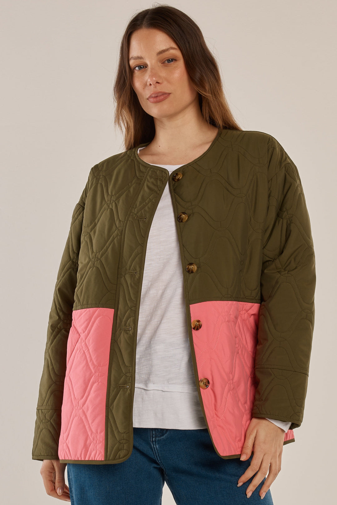 Woman wearing a green and pink quilted jacket on a beige background