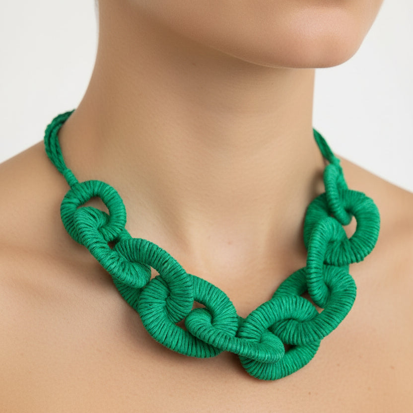 Green knitted necklace on a mannequin against a white background