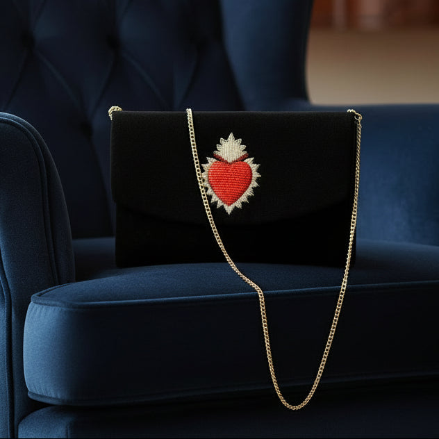 Black clutch bag with a red heart design on a white background