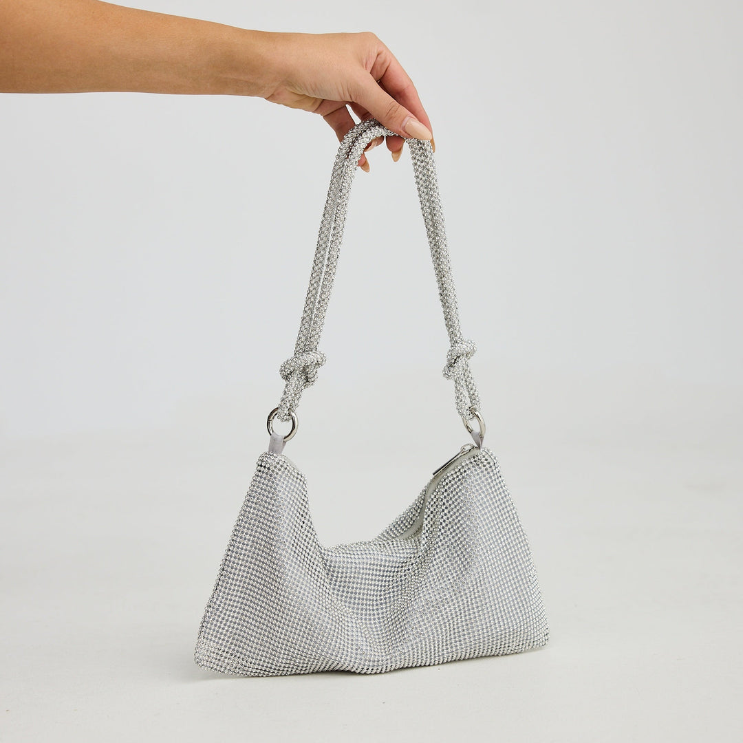 Hand holding a textured gray handbag against a plain background