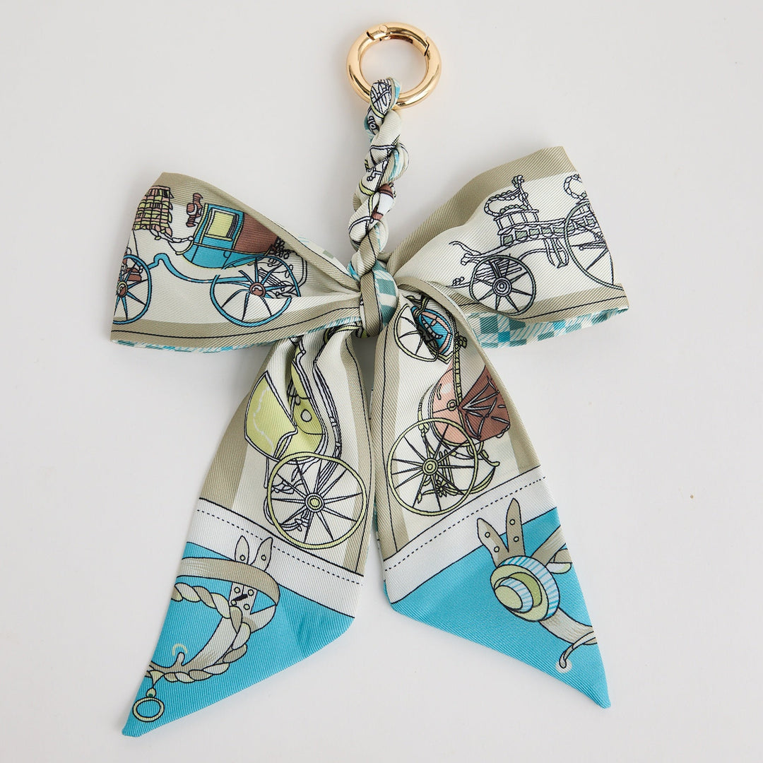Decorative bow keychain with vintage carriage design on a white background