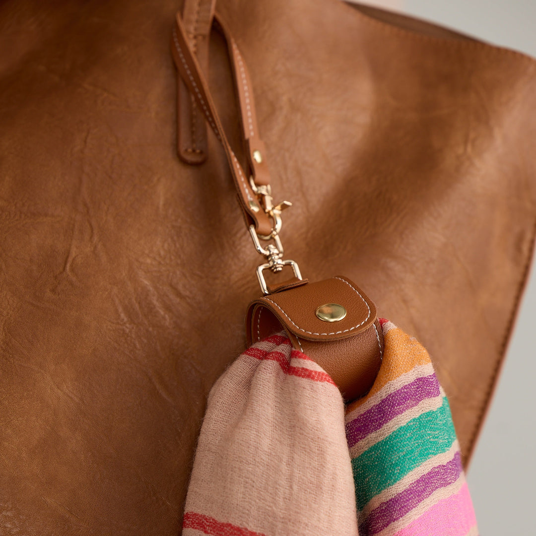 Brown leather bag with a colorful striped scarf draped over it