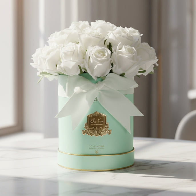 Mint green cylindrical hat box with white cote noire diffuser flowers and a white ribbon 