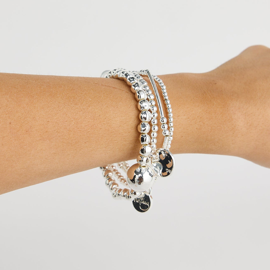 Person wearing a stack of bracelets on a plain background