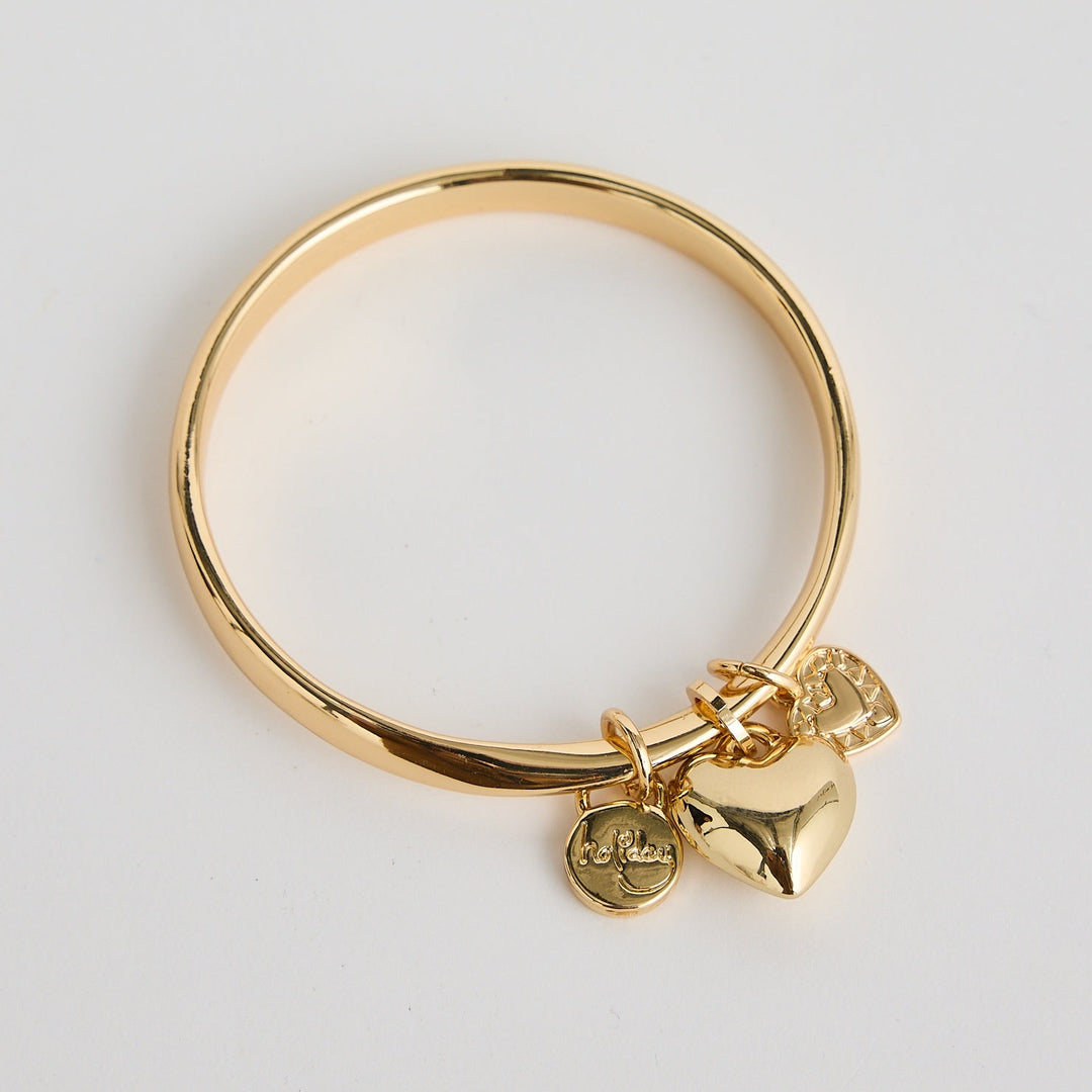 Gold ring with heart-shaped charm on a light gray background