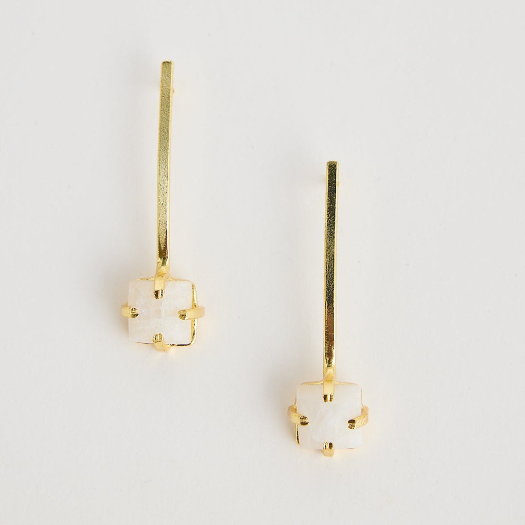 Pair of gold earrings with gemstones on a light gray background